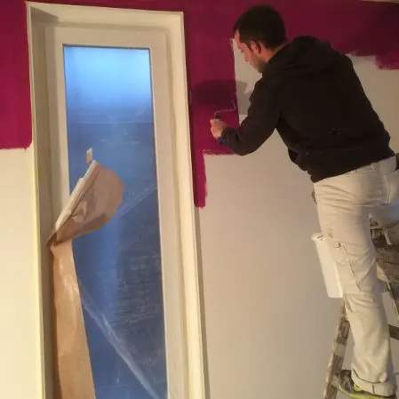 Maler beim Streichen einer Wand neben einer Tür